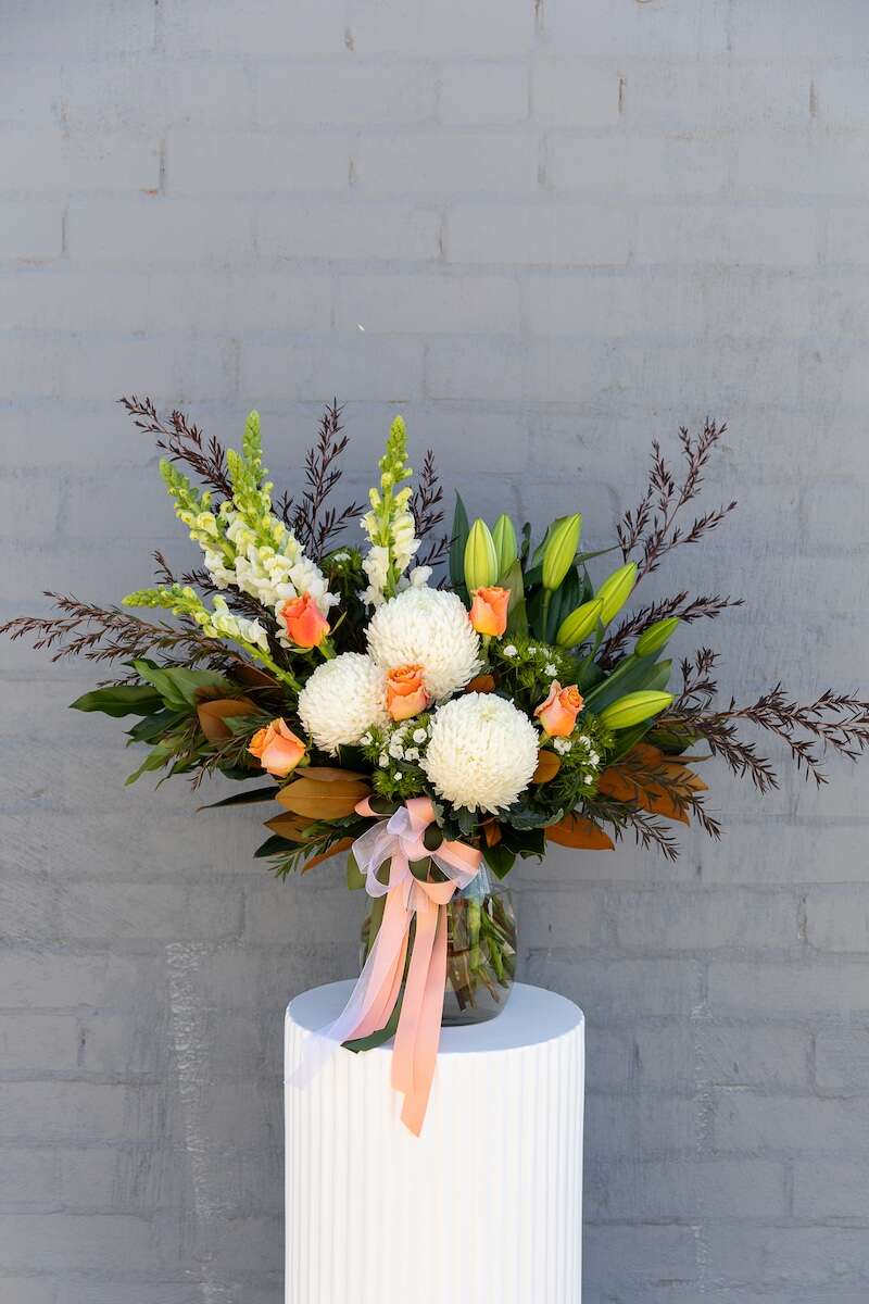 Christobelle - a modern-style vase arrangement with white lilies, apricot roses and snapdragons. Comes with a complementary bow. Available to buy from Donvale Flower Gallery, Doncaster, Melbourne, VIC.