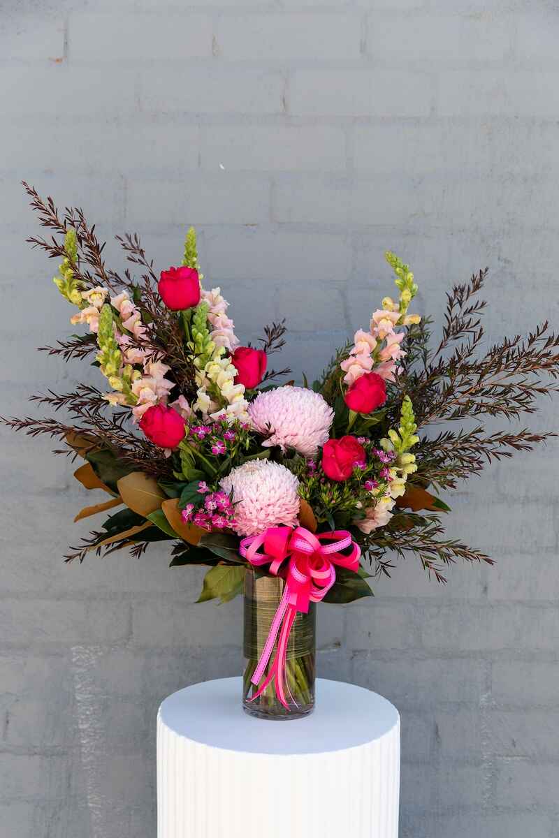 Image of Elizabeth: a modern pink-toned bouquet presented in a glass vase, adorned with a luxurious matching bow. 