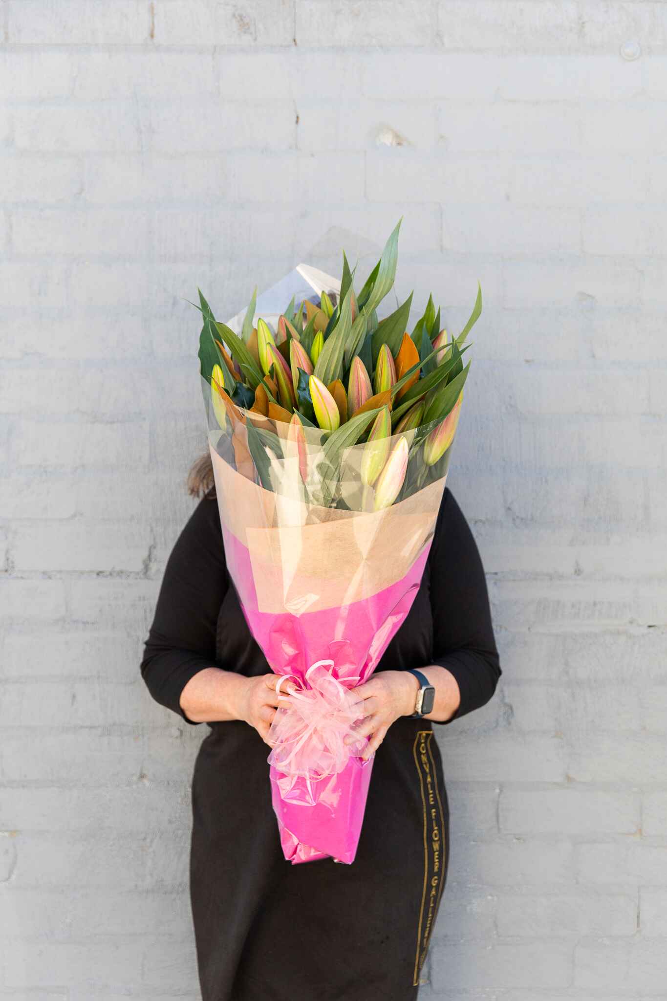 Image of a Donvale Flower Gallery team member holding the Lily flower bouquet which consists of two bunches of premium locally grown pink Oriental lilies.