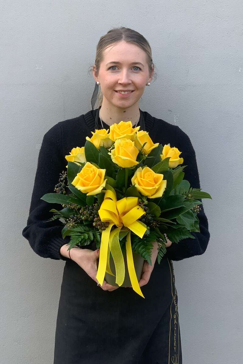 Image of a Donvale Flower Gallery team member holding the Rosie flower arrangement (consists of yellow roses).