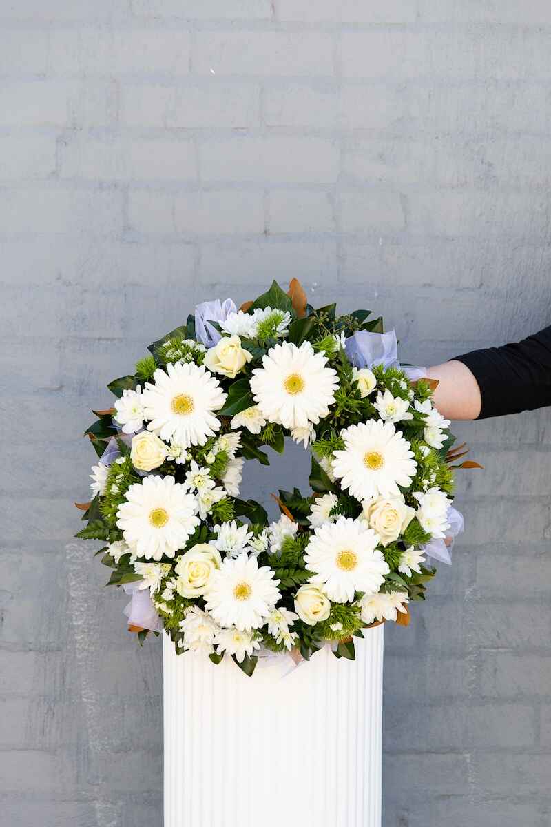 Image of a white and green flower wreath, perfect for funerals. Available to buy from Donvale Flower Gallery, Melbourne VIC (online or in-store).